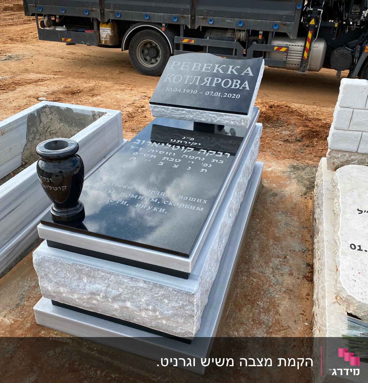 מצבה עם כיתוב בעברית ורוסית, אגרטל שחור על המצבה.